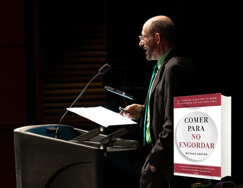 El Dr. Greger hablando en un podio bajo una luz