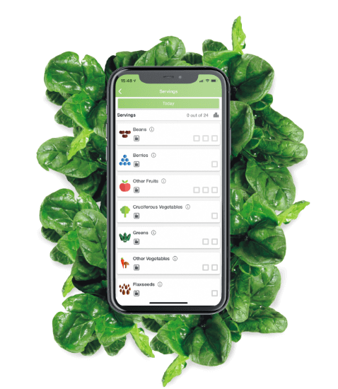 Phone with Daily Dozen app surrounded by greens