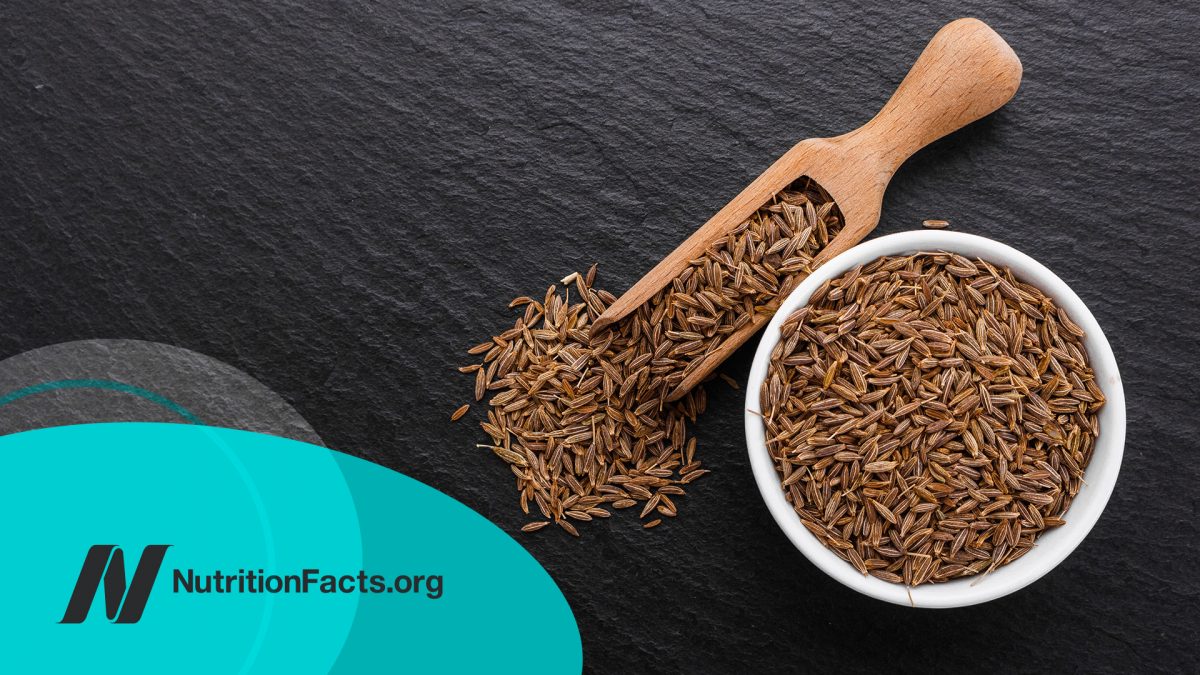 Cumin seeds in a bowl on a dark stone background