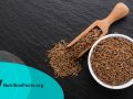 Cumin seeds in a bowl on a dark stone background