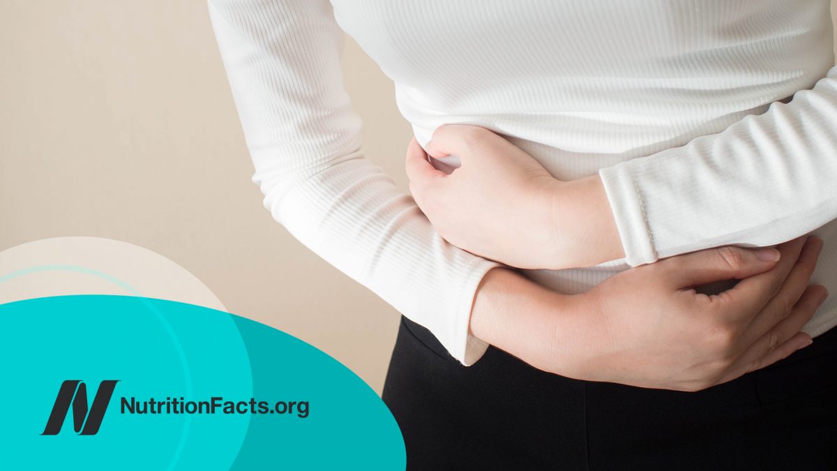 Young female suffering from stomach ache on gray background