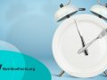 Plate as an Alarm clock with knife and fork as clock hands on blue background