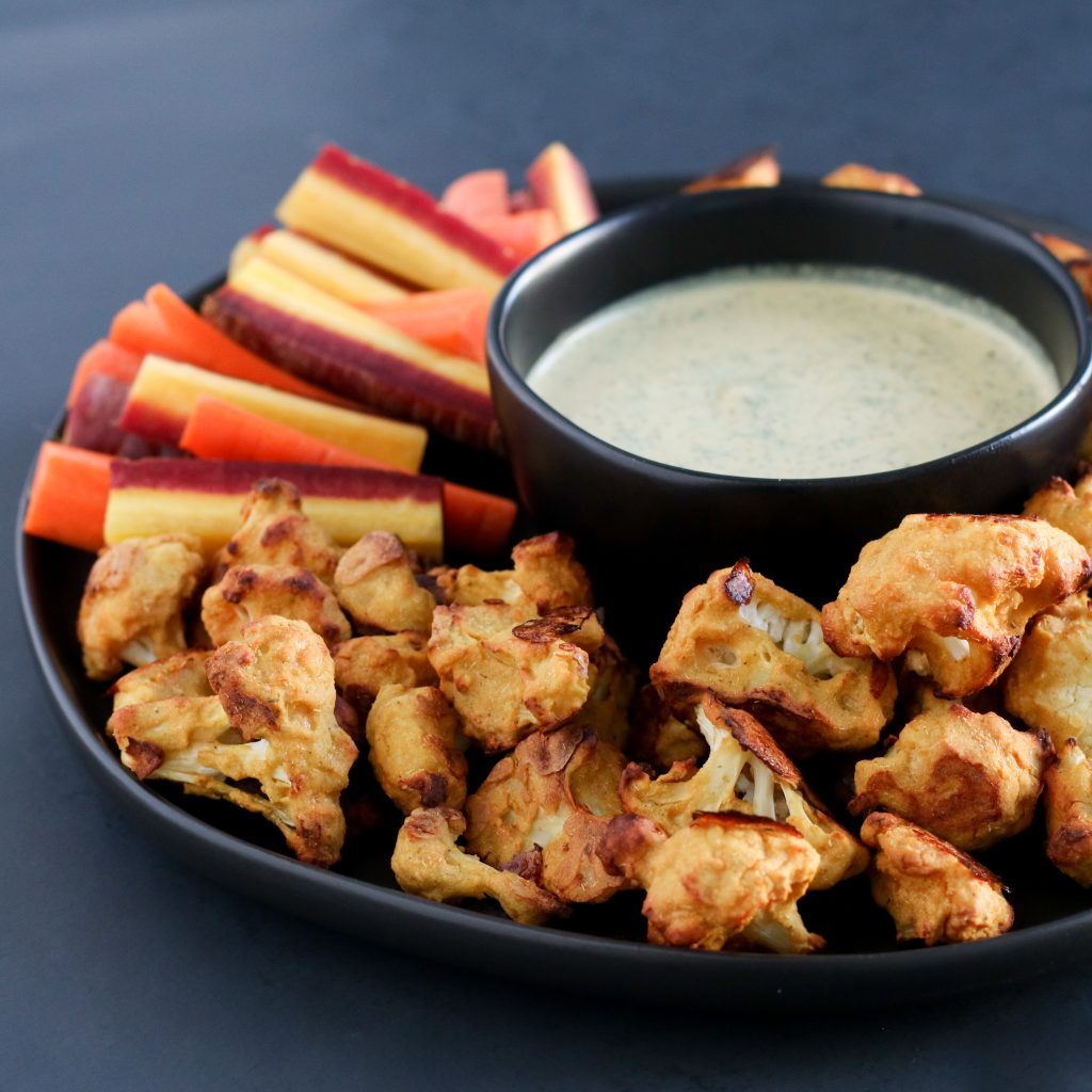 Cauliflower buffalo wings and carrot sticks on a dark background