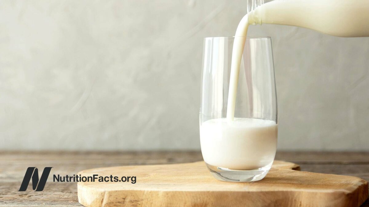 milk poured from a bottle into a glass cup on a wooden stand