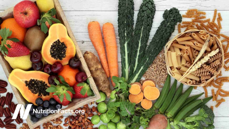 High-fiber plant-based foods with whole wheat pasta, nuts, fruits and vegetables on a rustic background