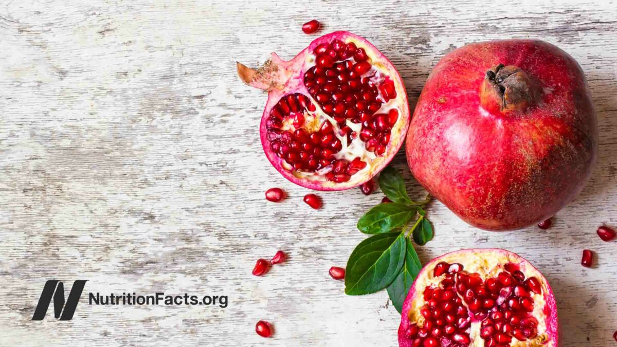 half pomegranate and ripe pomegranate fruit on white wooden rustic background