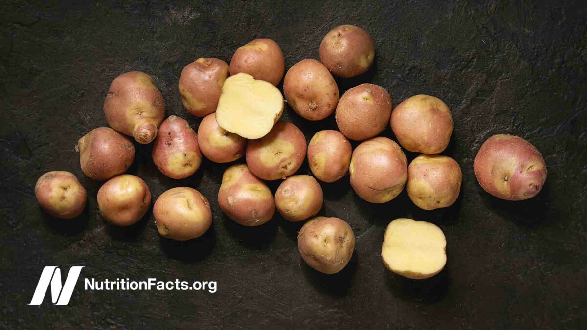 uncooked white potatoes named whole and sliced over dark texture background