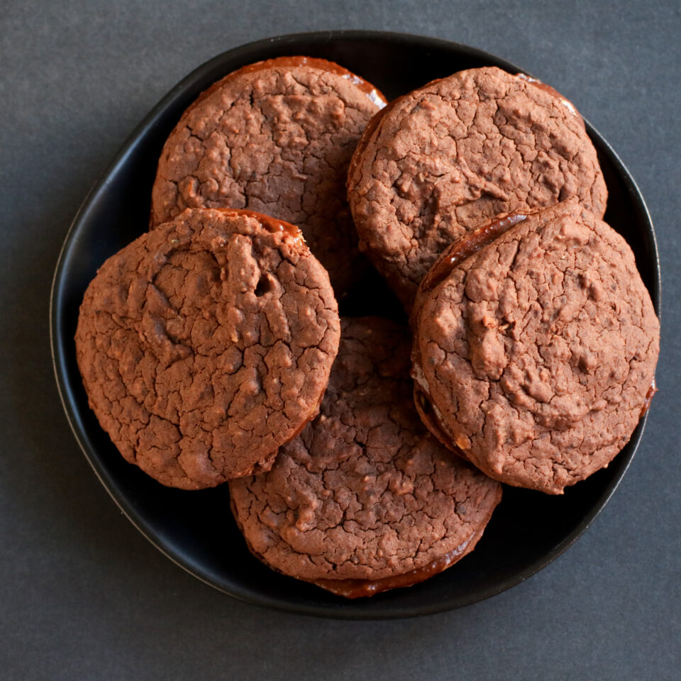 Five brownie cookie sandwiches stacked on a plate