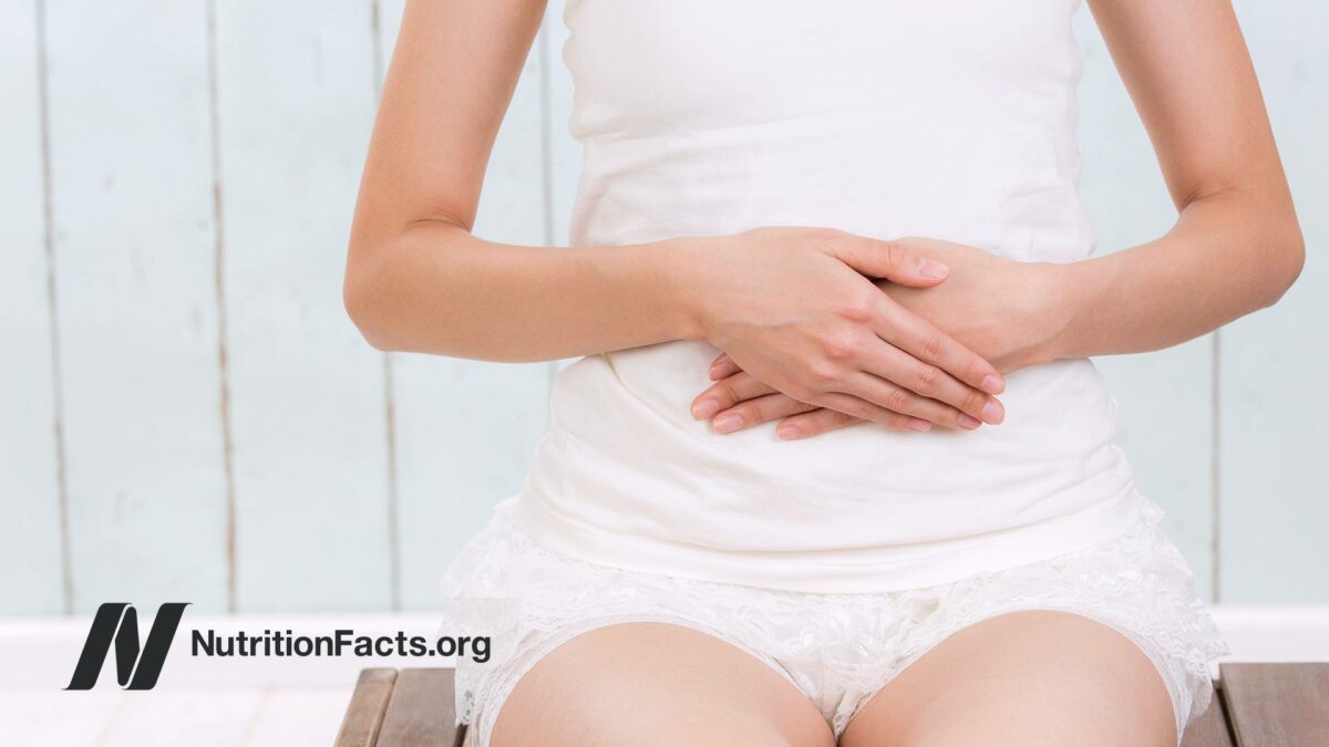 woman sitting while holding stomach