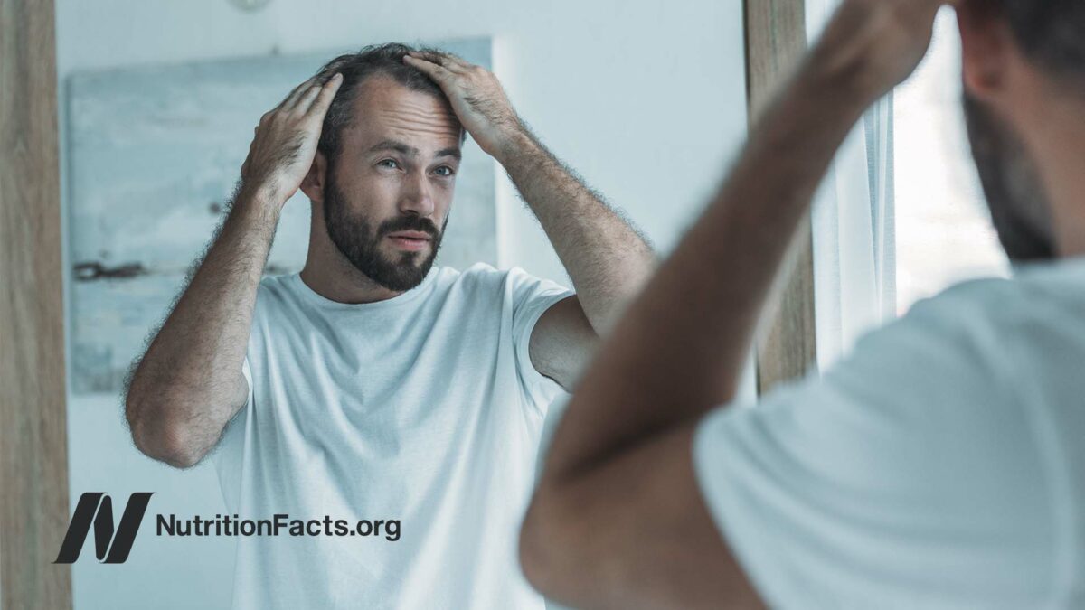 middle aged man with hair loss looking in mirror