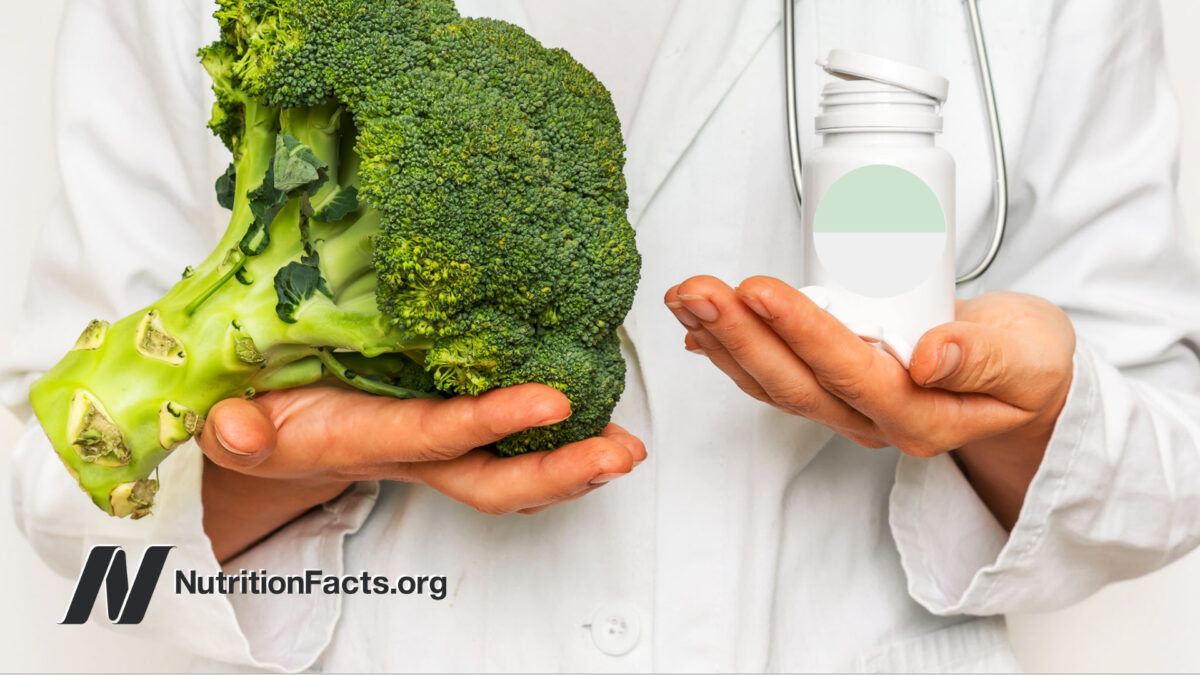 doctor holding broccoli in one hand and pill bottle in the other