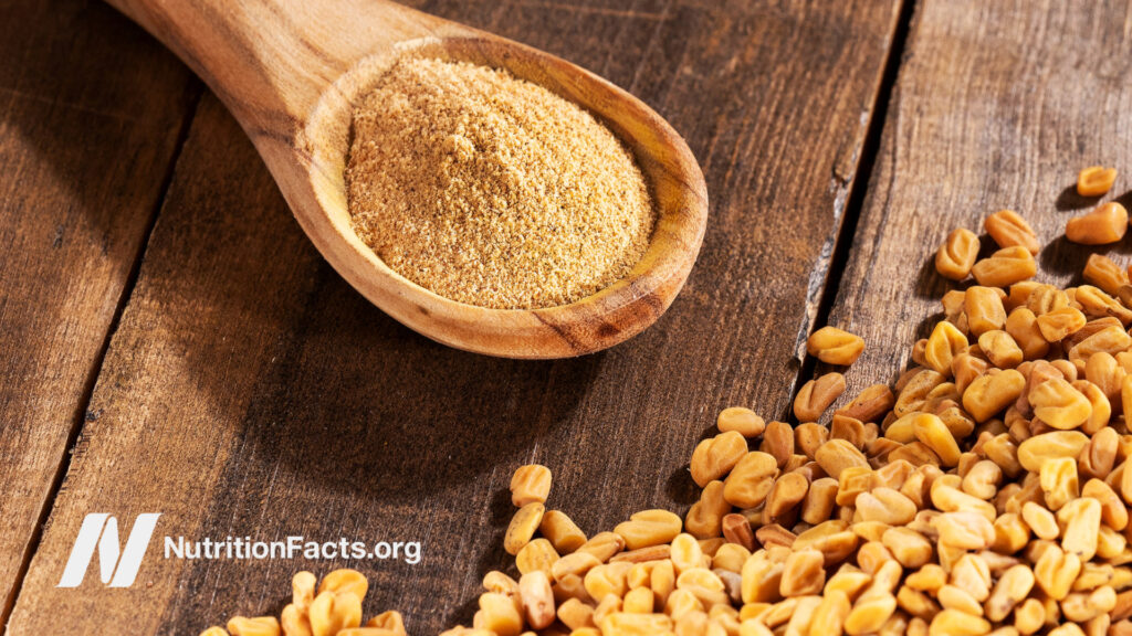 Spoon of fenugreek seeds on wooden table