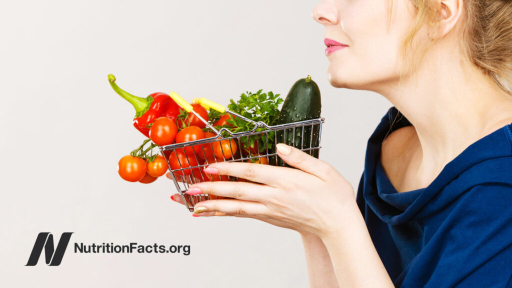 Woman smelling basket of vegetables