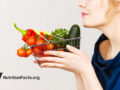 Woman smelling basket of vegetables