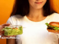 Woman choosing between salad and hamburger