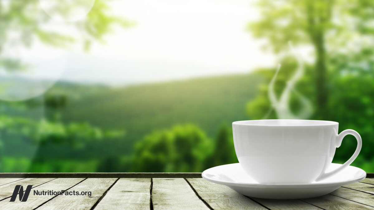 Teacup with steam rising in front of a serene nature background