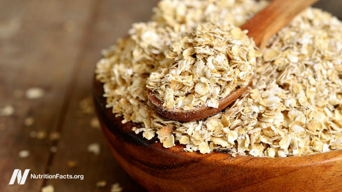 Dried oats in a wooden bowl with a measuring spoon