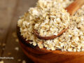 Dried oats in a wooden bowl with a measuring spoon