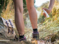 Person with hiking boots outside spraying their skin