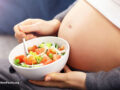 Pregnant person holding a white bowl of whole food
