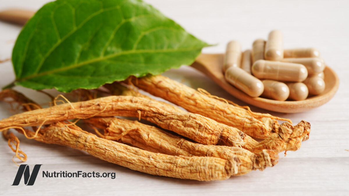 Ginseng root and supplement capsules on a white surface