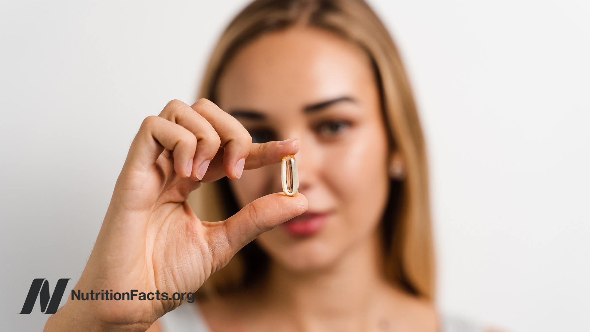 young woman holding a supplement pill