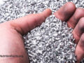 Hand scooping aluminum shavings from a pile