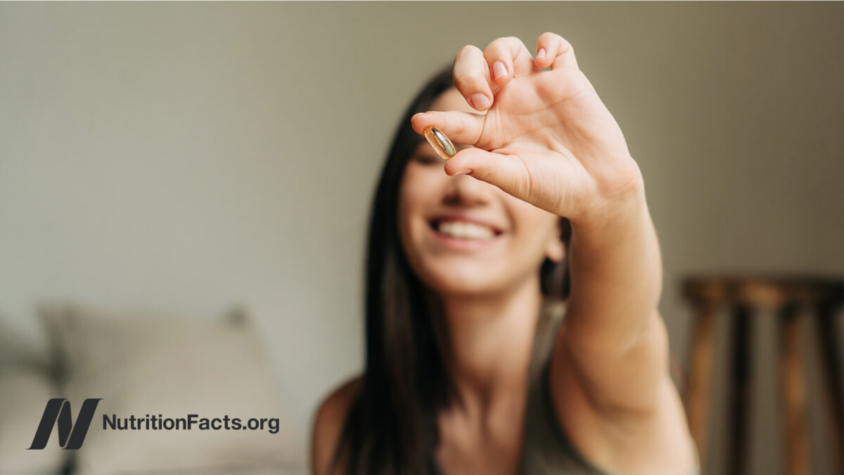 Woman smiling and holding out a liquid capsule