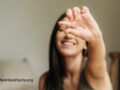 Woman smiling and holding out a liquid capsule