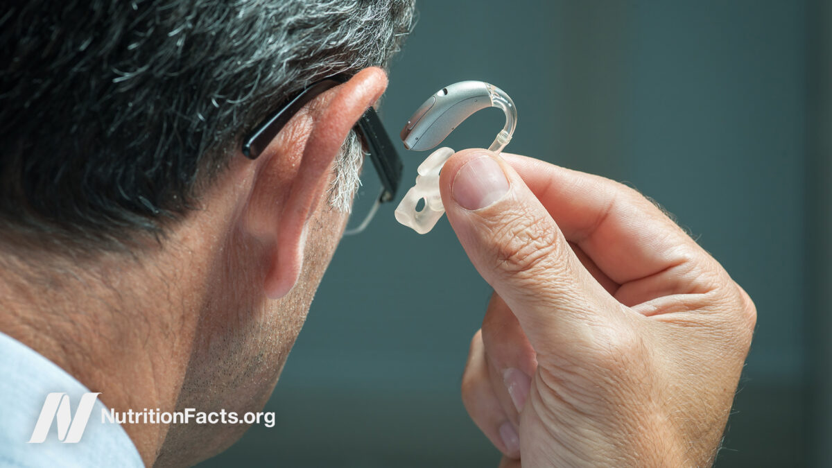 Older male inserting hearing aids in his ears