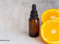 Fresh orange fruit and orange essential oil on concrete background