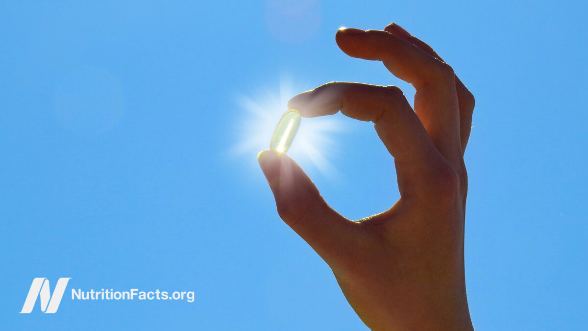 Holding a vitamin D supplement capsule with sun shining behind