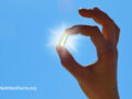 Holding a vitamin D supplement capsule with sun shining behind