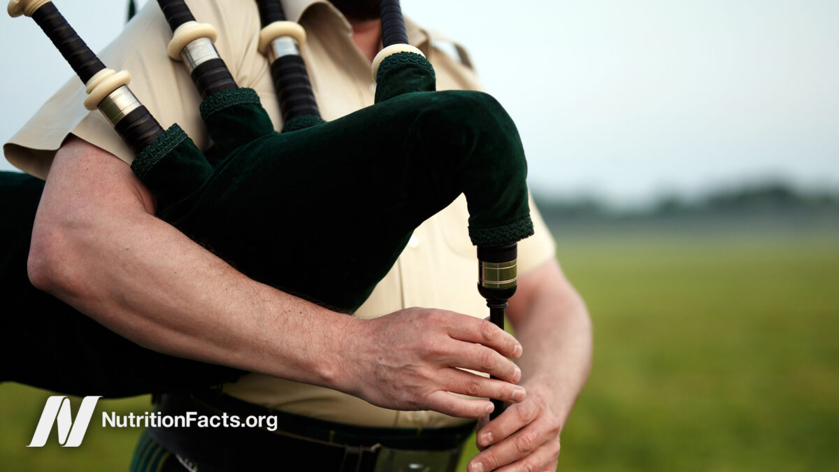 Close up view of someone playing bagpipes in a calm outdoor environment