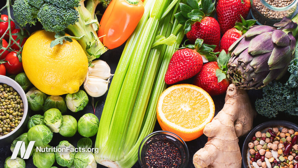 A variety of colorful fruits, vegetables and legumes on a flat surface