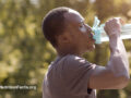 Person outdoors drinking water from a water bottle