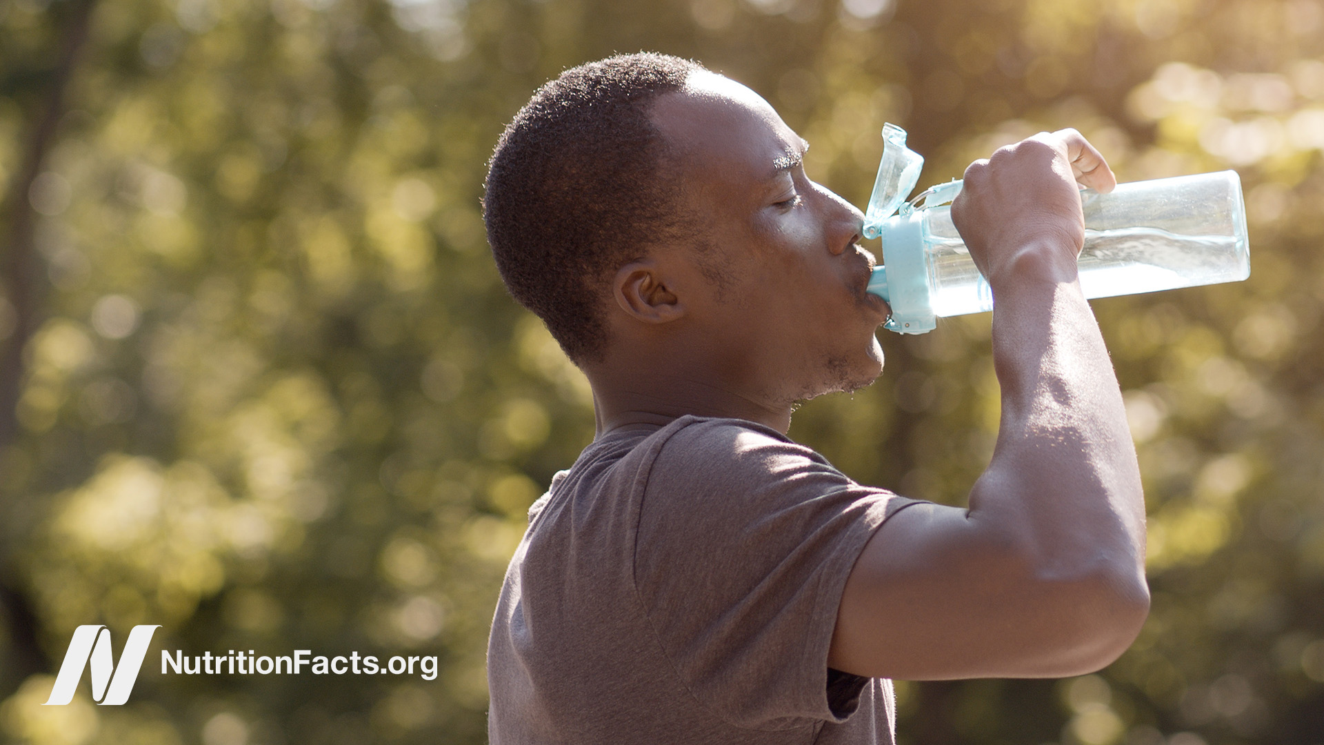 Person outdoors drinking water from a water bottle