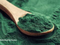 Spirulina powder scooped up with a wooden spoon