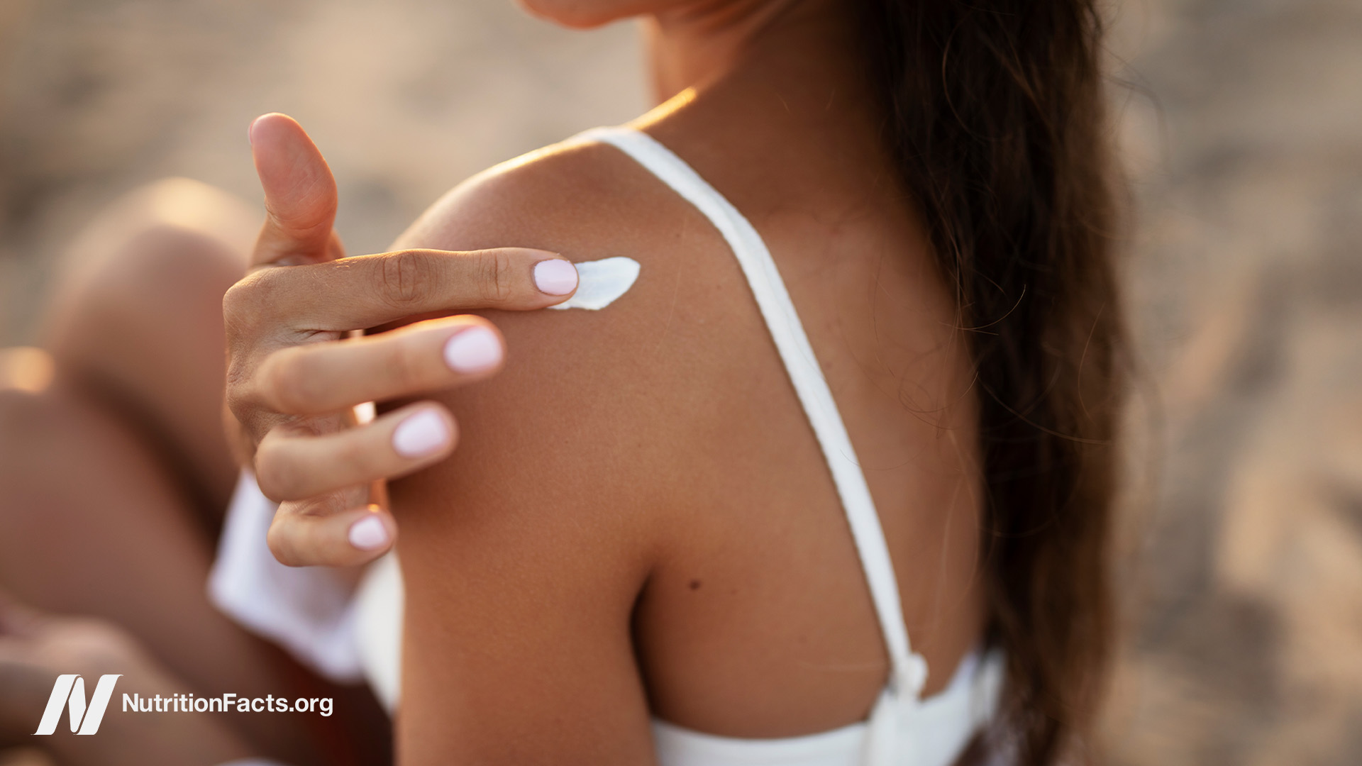 Woman applying sunscreen to her shoulder
