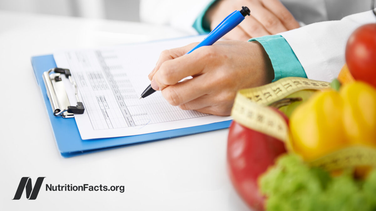 Doctor filling out paperwork with fresh vegetables nearby