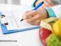 Doctor filling out paperwork with fresh vegetables nearby