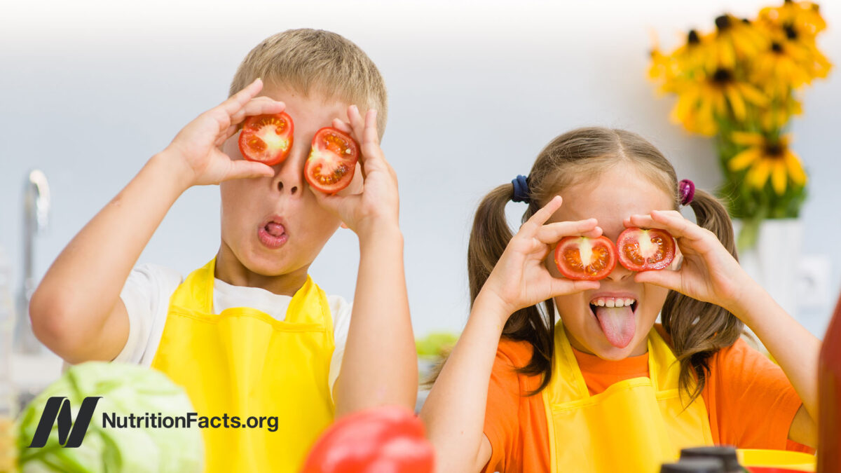 Two children making funny faces and holding tomato slices over their eyes