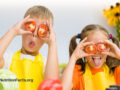 Two children making funny faces and holding tomato slices over their eyes