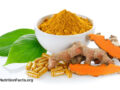 White bowl of ground turmeric powder behind fresh turmeric roots and turmeric supplement capsules