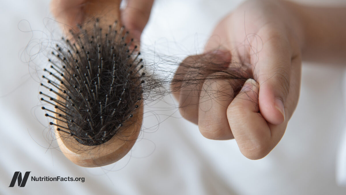 person pulling loose hair out of a brush