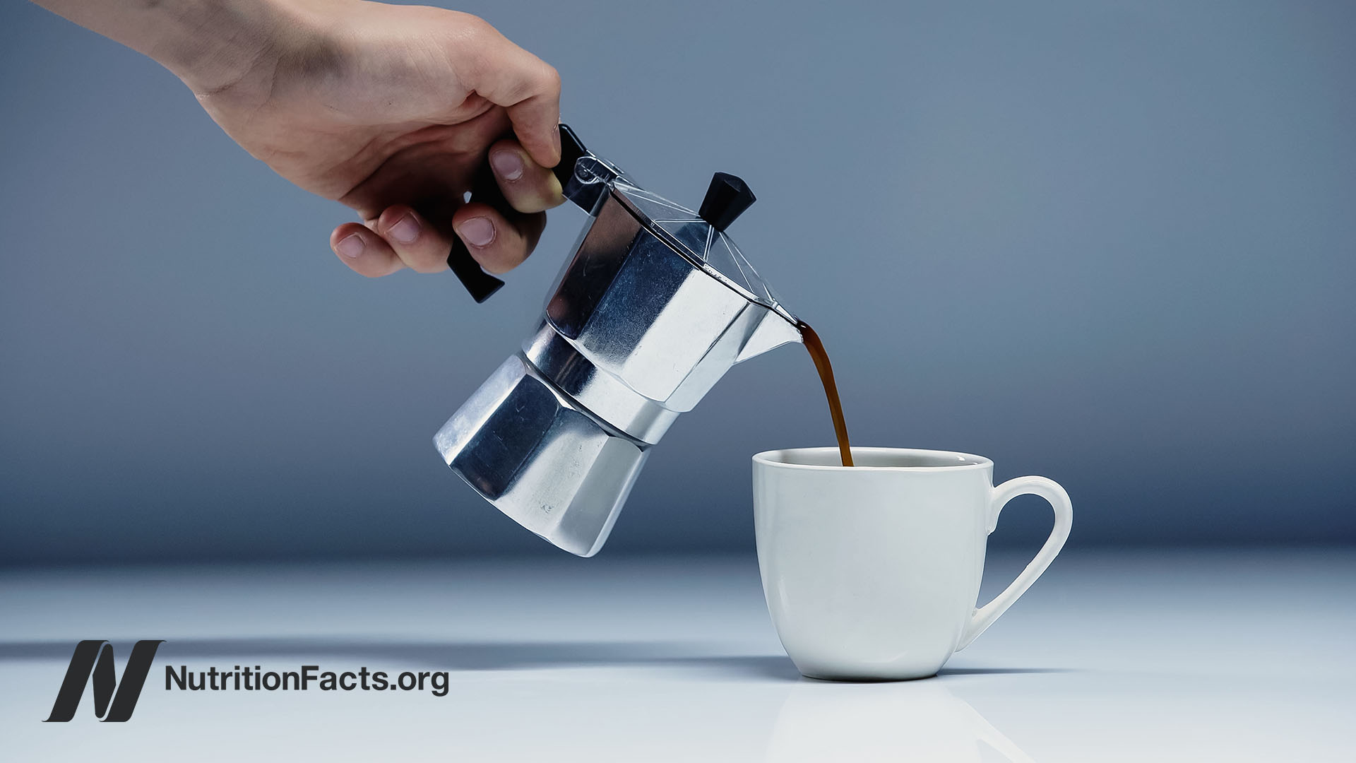 Hand holding a Moka pot pouring hot coffee into a white mug
