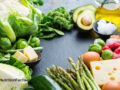 Various vegetables, cheeses, and meats on a dark counter