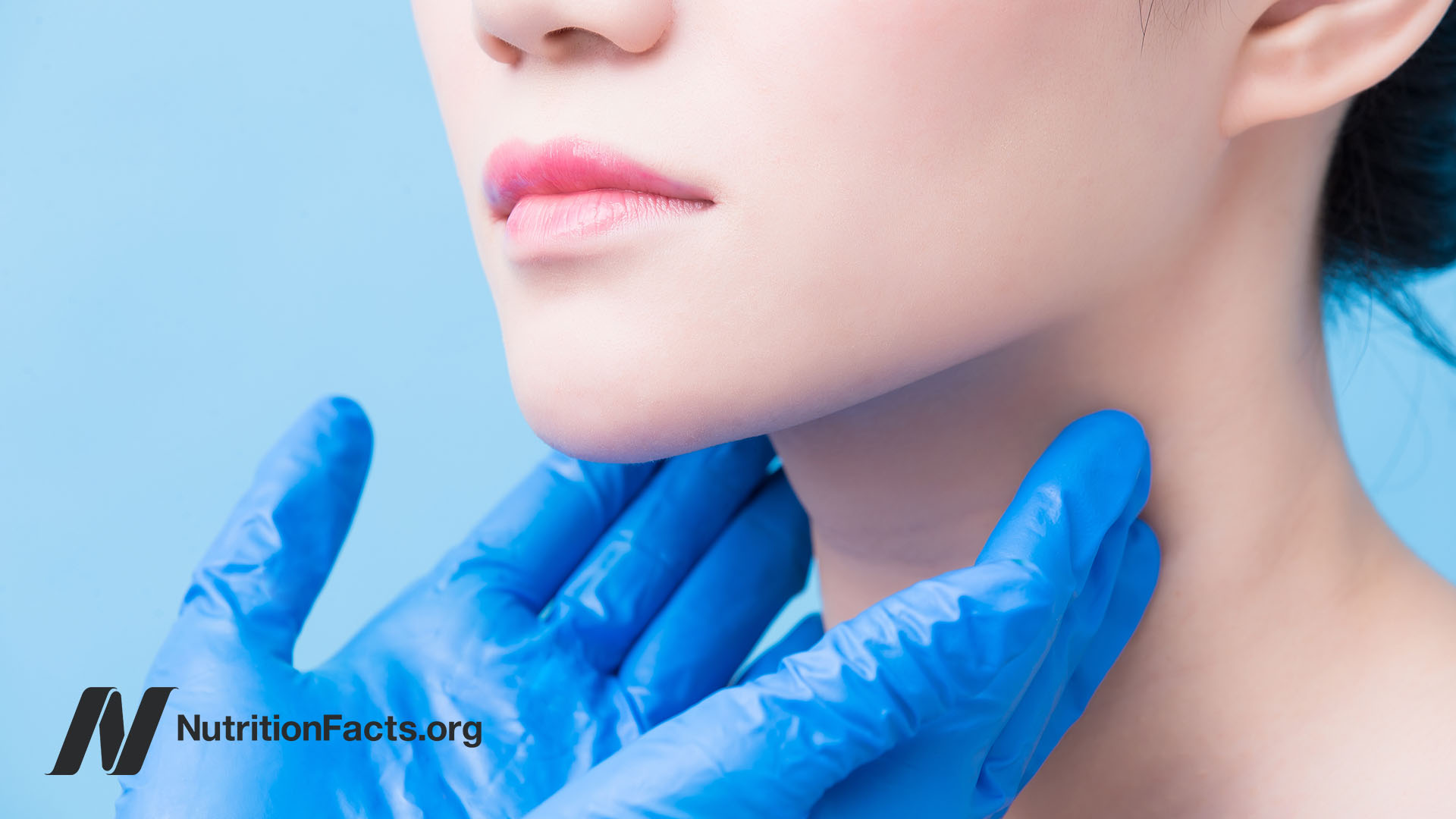 Hands with blue gloves hovering over a person’s thyroid area