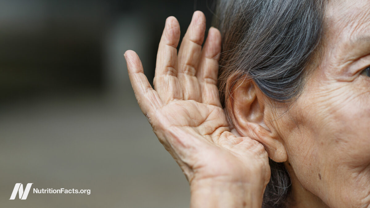 Elderly person holding their hand up to their ear