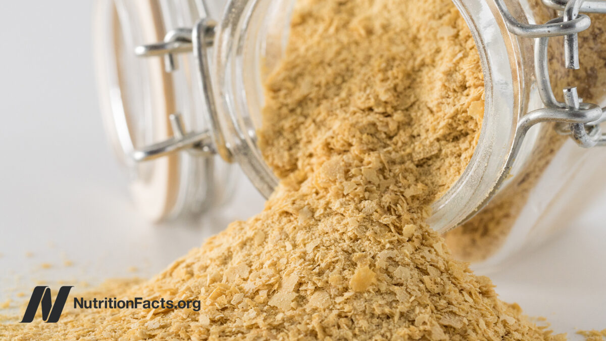 Large glass jar pouring out a pile of nutritional yeast